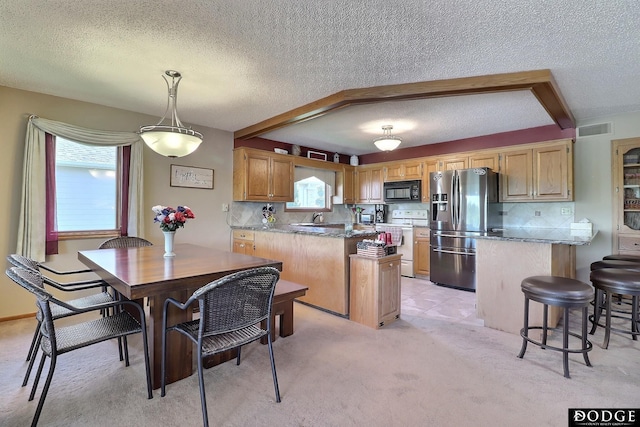 dining area featuring a wealth of natural light, a textured ceiling, light colored carpet, and visible vents
