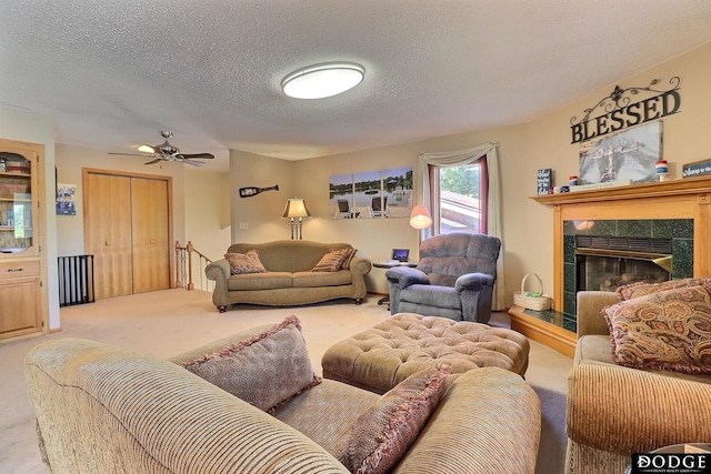 living room with a fireplace, ceiling fan, carpet floors, and a textured ceiling