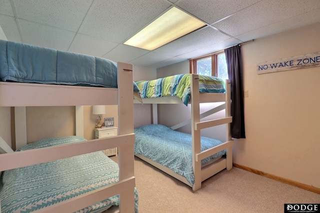 bedroom with carpet floors, baseboards, and a paneled ceiling