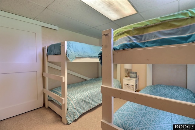 carpeted bedroom featuring a drop ceiling