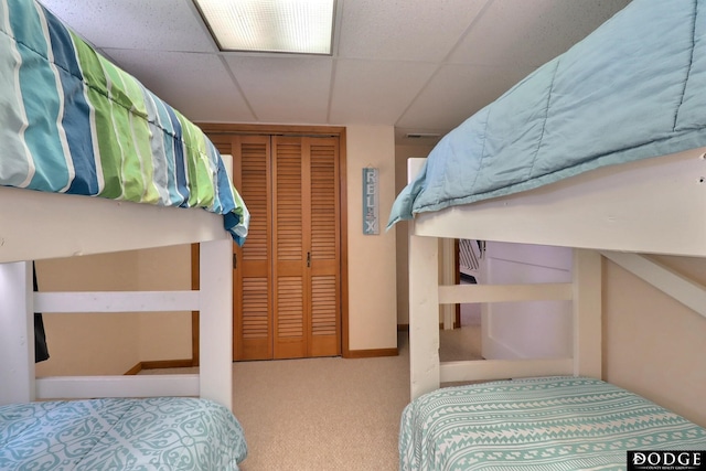 carpeted bedroom with a closet and a drop ceiling