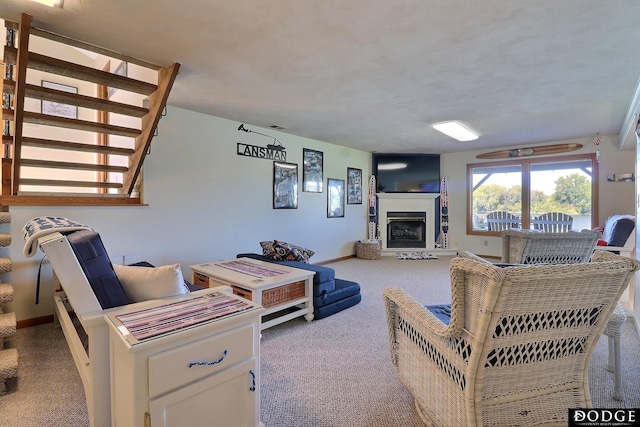 living area with carpet flooring, baseboards, a fireplace with raised hearth, and stairway