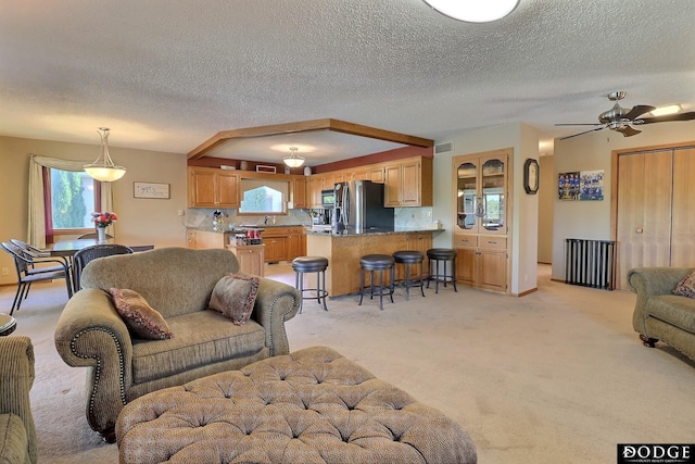 living area with light carpet, a textured ceiling, visible vents, and a ceiling fan