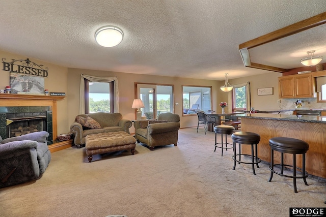 living area featuring light carpet, beamed ceiling, a fireplace, and a wealth of natural light
