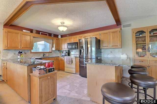 kitchen featuring white electric stove, black microwave, stainless steel fridge, a peninsula, and visible vents