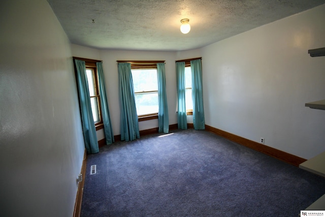 carpeted spare room with baseboards, visible vents, and a textured ceiling