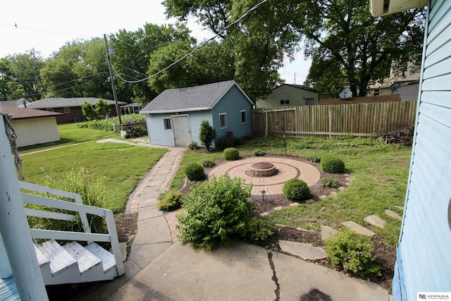 view of yard with a patio, an outbuilding, a fire pit, and fence