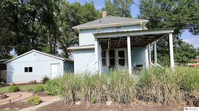 back of property with a chimney and an outbuilding