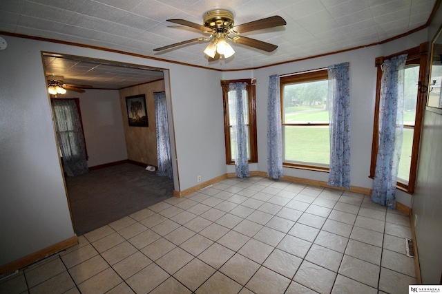 spare room featuring a ceiling fan, ornamental molding, baseboards, and light tile patterned floors