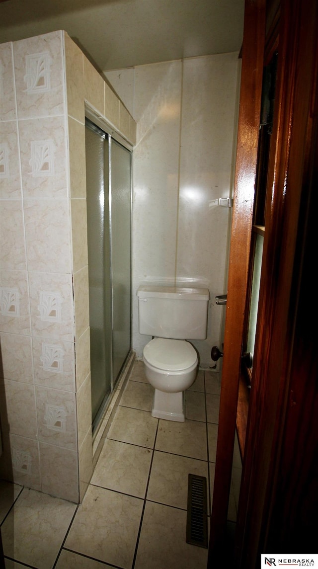 bathroom featuring visible vents, toilet, tile patterned floors, and a stall shower