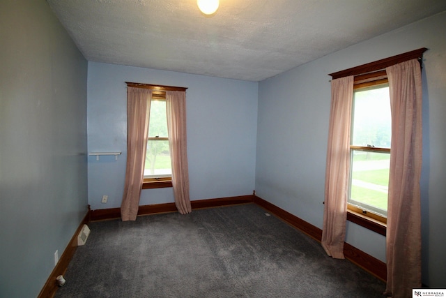 spare room featuring baseboards, dark colored carpet, and a textured ceiling