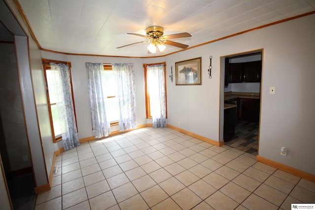 empty room with light tile patterned flooring, baseboards, crown molding, and ceiling fan