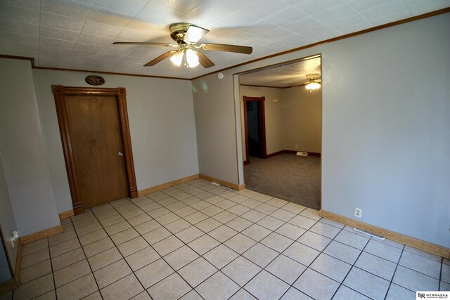 unfurnished room featuring light tile patterned floors, crown molding, baseboards, and ceiling fan