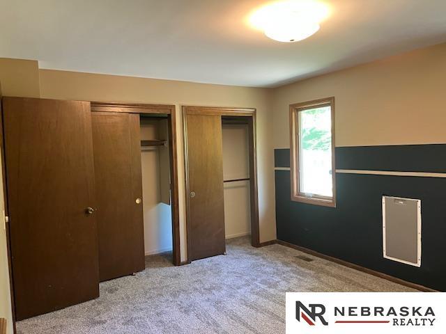 9406 Parker St, Omaha, NE 68114 - unfurnished bedroom featuring two closets and light carpet