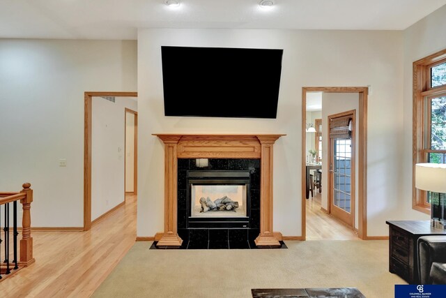 carpeted living room featuring baseboards, a fireplace, and wood finished floors