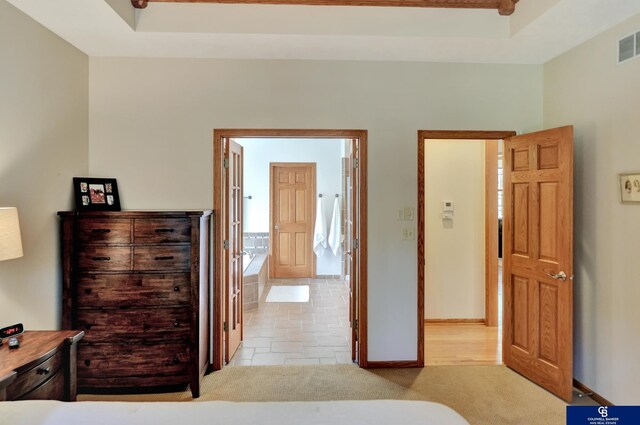 bedroom featuring light colored carpet, a tray ceiling, and baseboards