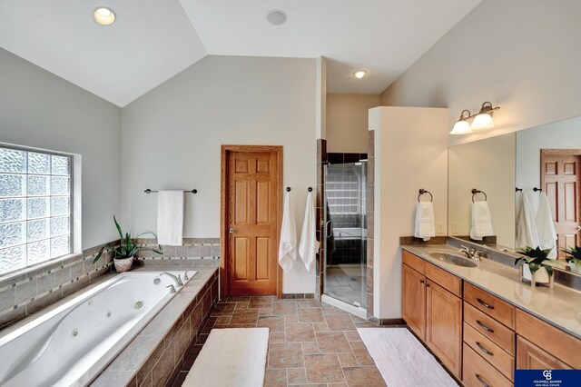 bathroom featuring vaulted ceiling, vanity, a jetted tub, a shower stall, and baseboards