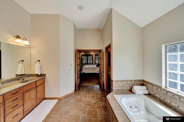 full bath with stone finish floors, a jetted tub, vanity, connected bathroom, and baseboards