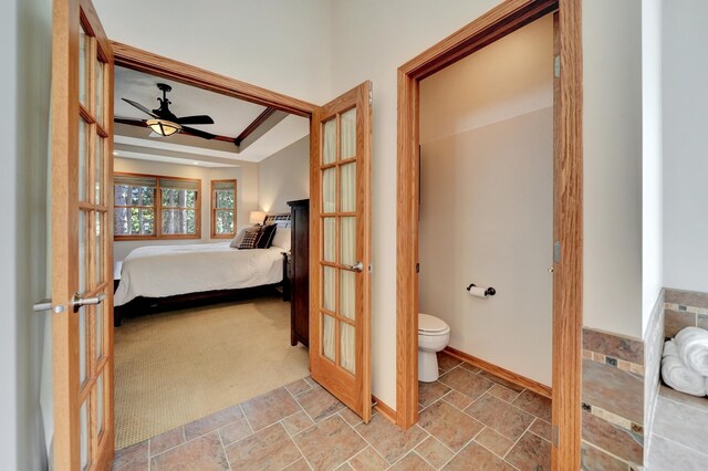 bathroom featuring toilet, ensuite bath, a ceiling fan, french doors, and stone finish floors