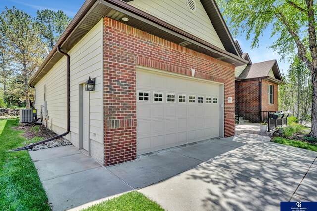 view of property exterior featuring brick siding, central air condition unit, concrete driveway, and a garage