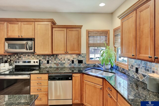 kitchen featuring stainless steel appliances, a sink, dark stone counters, decorative backsplash, and recessed lighting