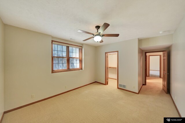 spare room with light colored carpet, ceiling fan, and baseboards