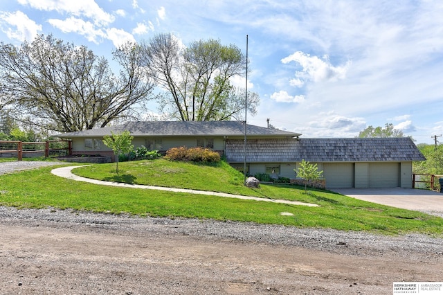 view of front of house featuring driveway, fence, a front lawn, and a garage