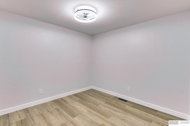 empty room featuring baseboards, light wood finished floors, and visible vents