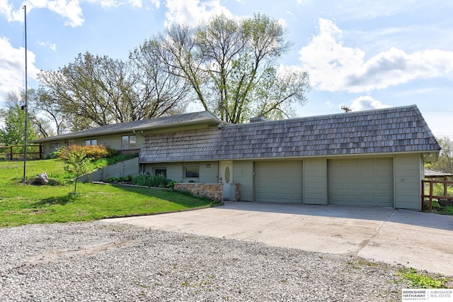 view of front of house with fence, a front yard, mansard roof, concrete driveway, and an attached garage