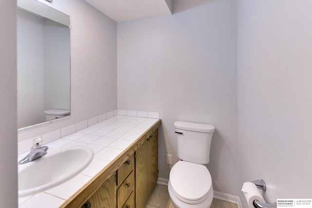 half bathroom featuring toilet, baseboards, and vanity