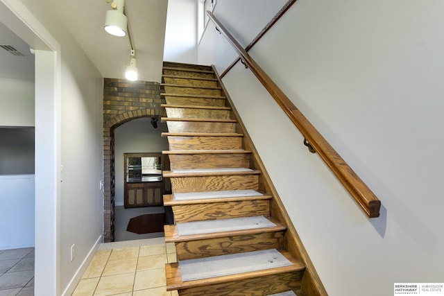 stairway with tile patterned floors, arched walkways, and visible vents
