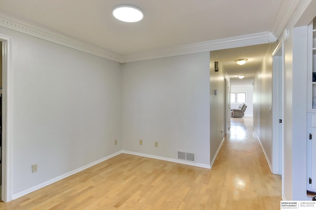 empty room with baseboards, visible vents, ornamental molding, and light wood-style flooring