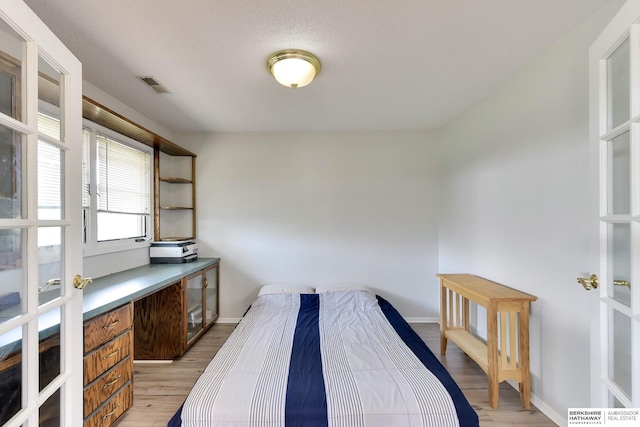 bedroom featuring baseboards, light wood-type flooring, and visible vents
