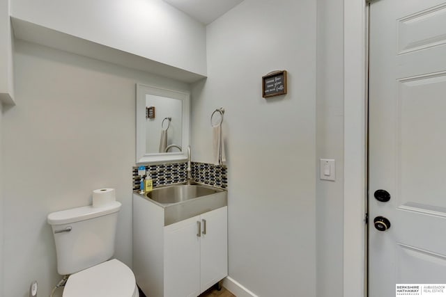 bathroom featuring vanity, decorative backsplash, and toilet