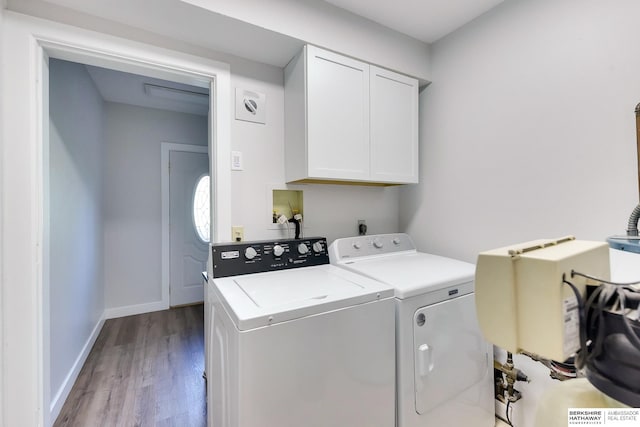 laundry room featuring baseboards, washing machine and dryer, cabinet space, and wood finished floors