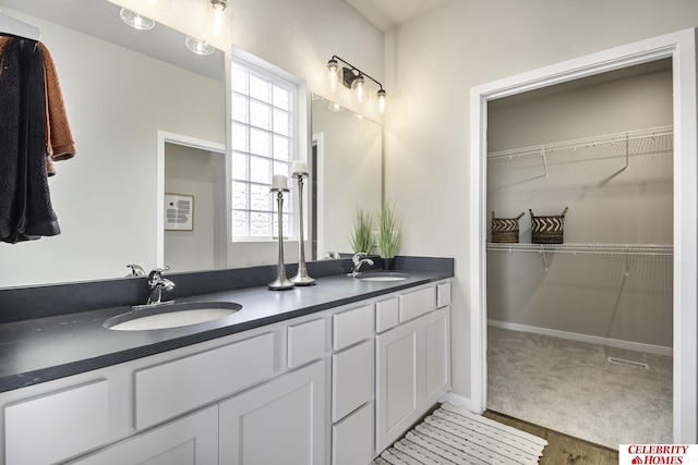 full bathroom with double vanity, a spacious closet, and a sink