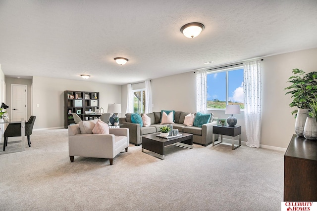 living room featuring light carpet, baseboards, and a textured ceiling