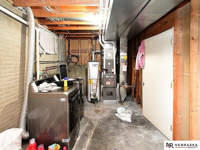 unfinished basement featuring water heater, heating unit, independent washer and dryer, and brick wall