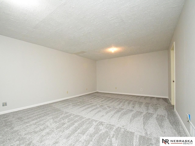 carpeted spare room featuring baseboards and a textured ceiling