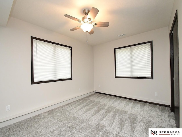 spare room with baseboards, carpet floors, ceiling fan, and visible vents