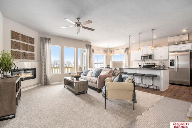 16925 Curtis Ave, Omaha, NE 68116 - living area featuring light colored carpet, baseboards, a textured ceiling, a ceiling fan, and a glass covered fireplace