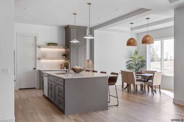 kitchen with gray cabinetry, light countertops, a sink, and open shelves