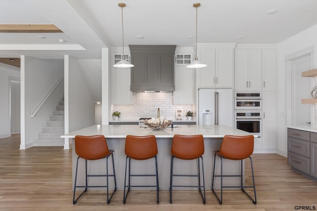 kitchen featuring light countertops, light wood-style flooring, tasteful backsplash, and white appliances