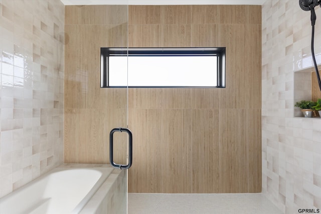 full bath featuring tile walls, a garden tub, and a shower stall