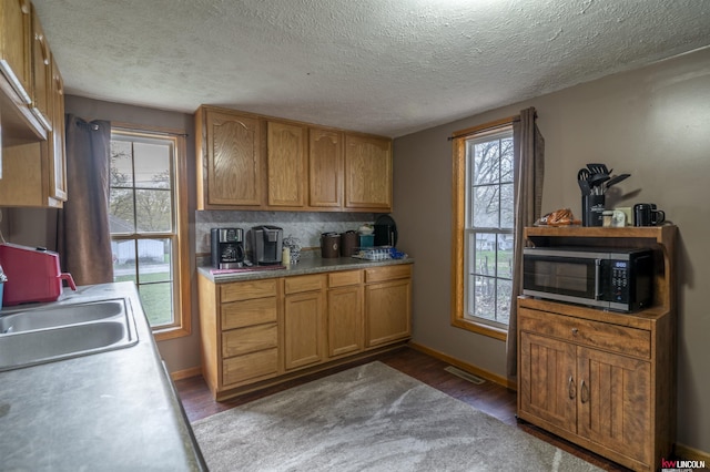 kitchen featuring light countertops, baseboards, a sink, dark wood-style floors, and backsplash