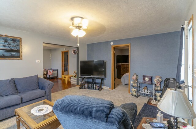 living area featuring a ceiling fan and a textured ceiling