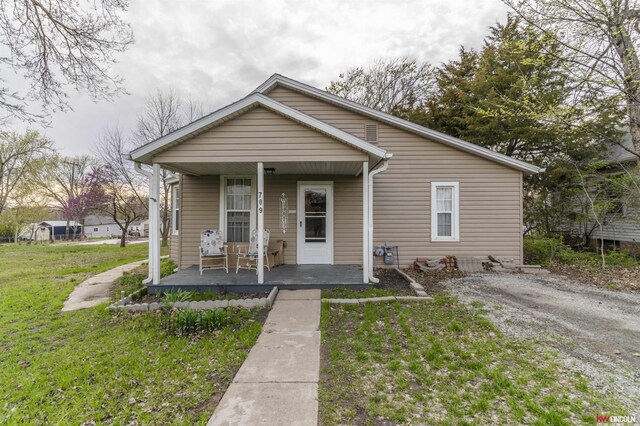 bungalow-style house with a front lawn and covered porch