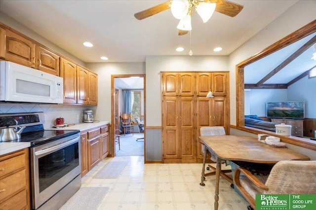 kitchen featuring light countertops, ceiling fan, electric stove, white microwave, and light floors