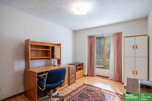 home office with baseboards, light wood-style floors, a textured ceiling, and visible vents