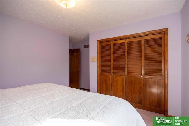 carpeted bedroom with a textured ceiling, a closet, and visible vents